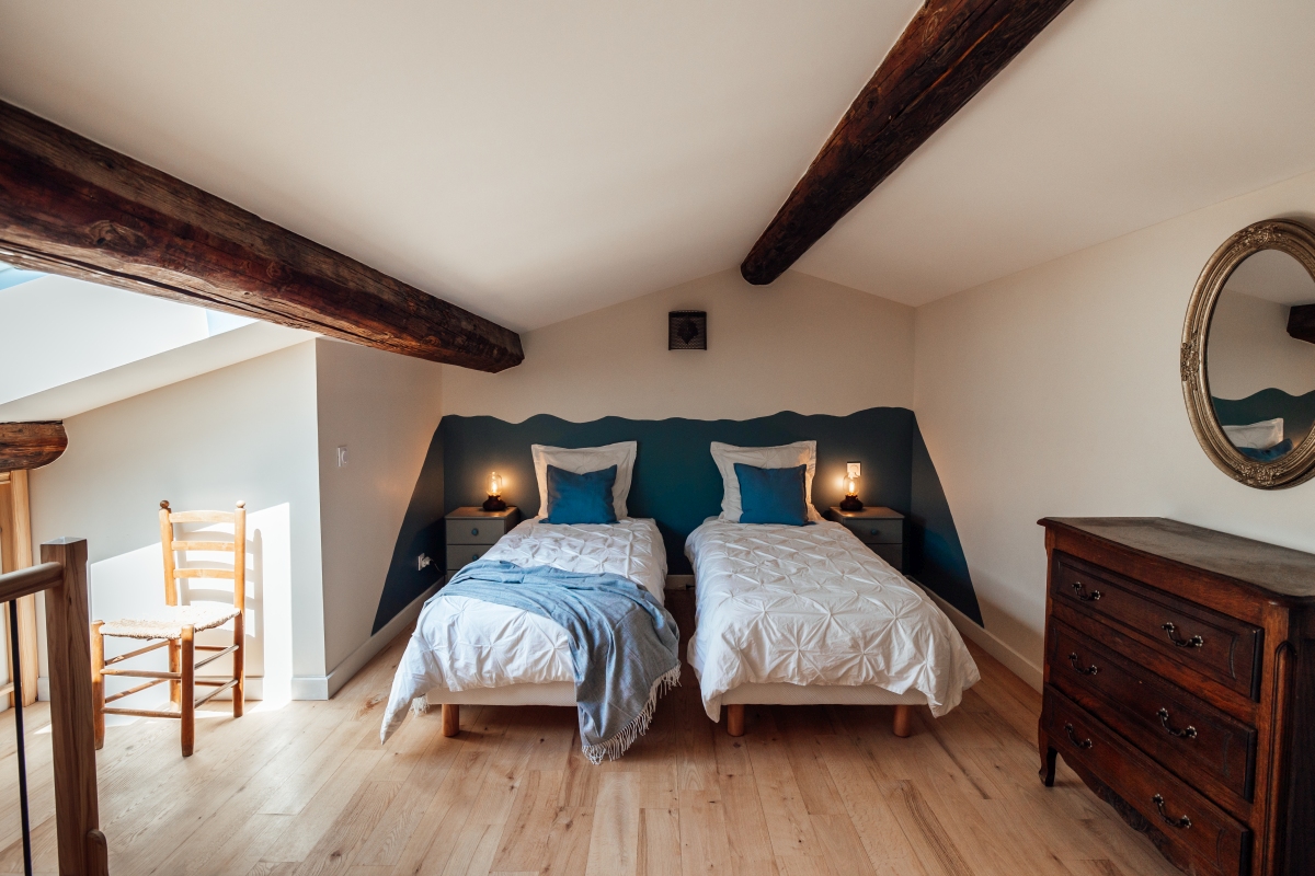 La mezzanine de la grande chambre du gite familial Garance La mezzanine et son grand lit avec la tete de lit bleu, poutres apparentes et meubles vintage