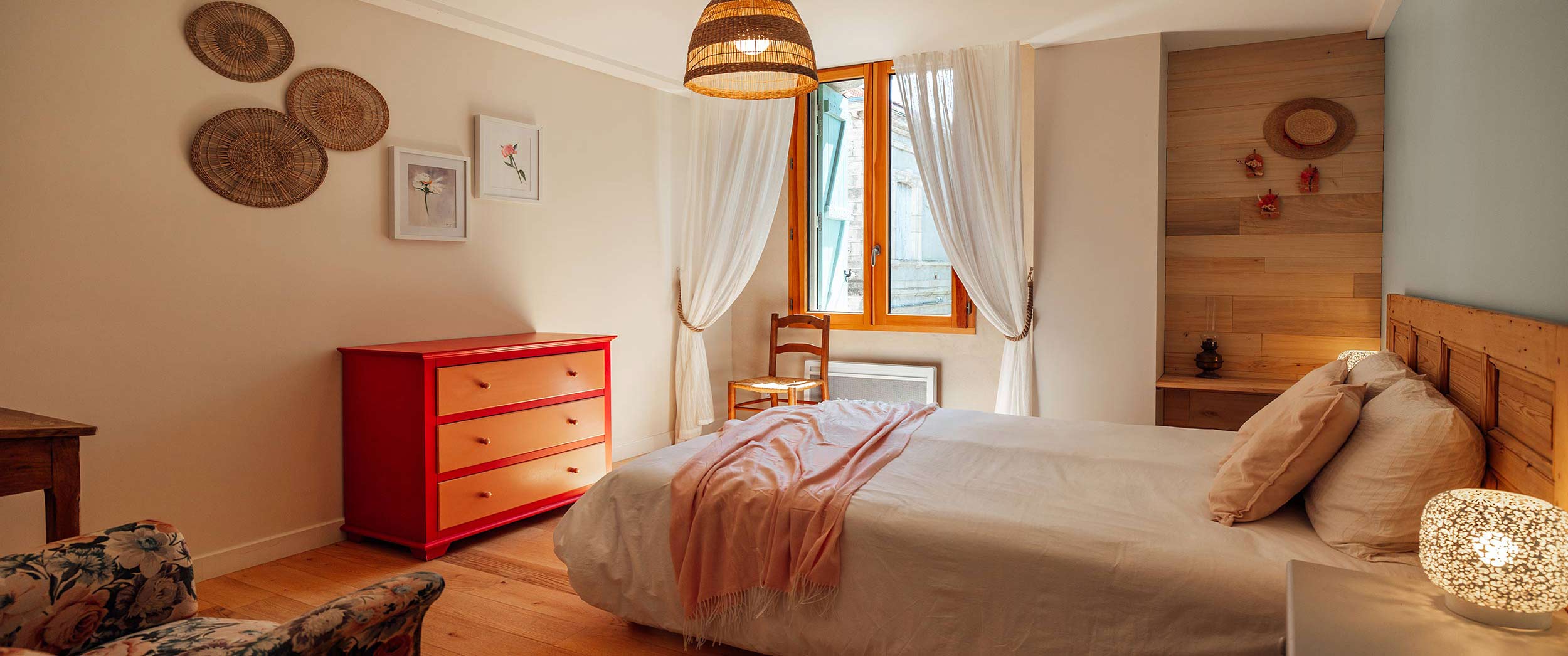Jolie chambre parentale du gîte Garance La jolie chambre aux couleurs rouge et rose avec mobilier chinée et vue sur le domaine viticole