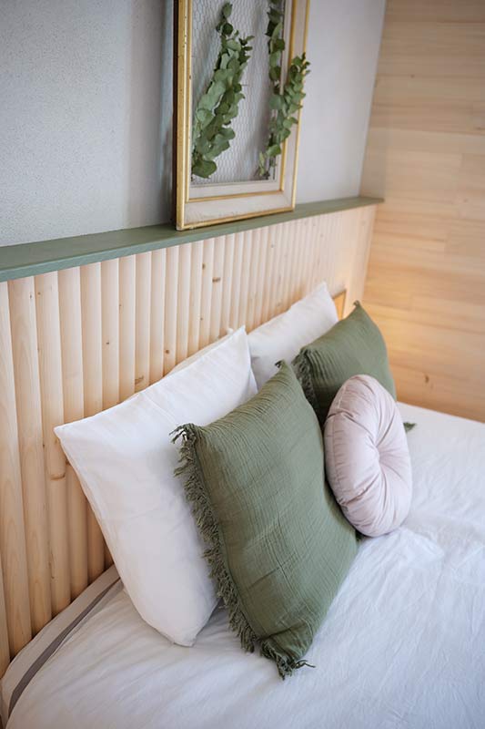 Tête de lit avec courbe en bois et décoration verte du grand gîte