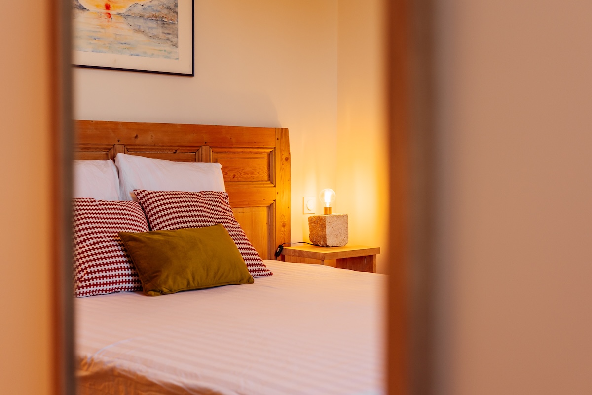 Effet de miroir dans la chambre aux couleurs moutarde et bordeaux ainsi que sa tête de lit en bois