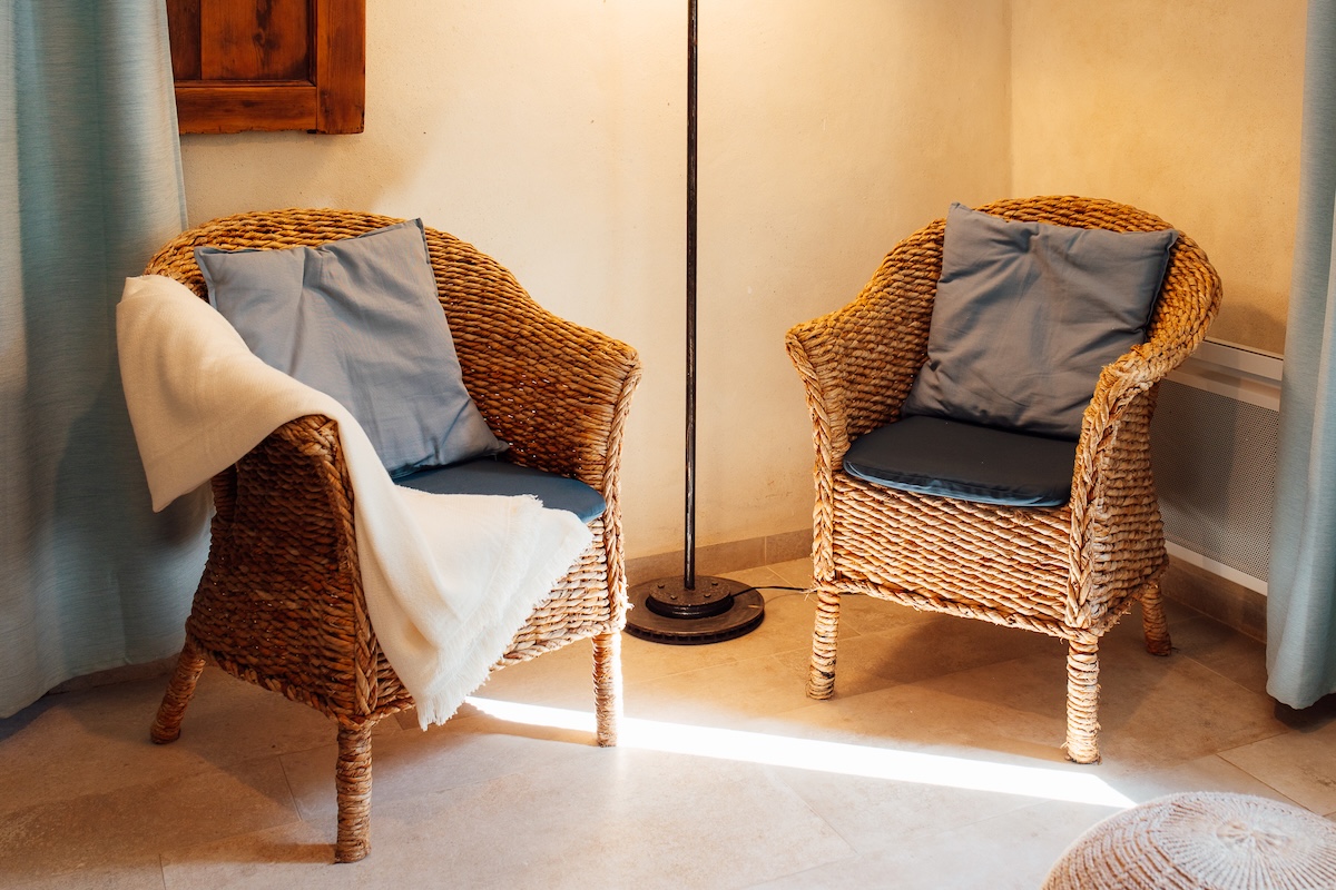 Dans le gîte pour 2 personnes, deux jolis fauteuils en osier et coussins bleus 